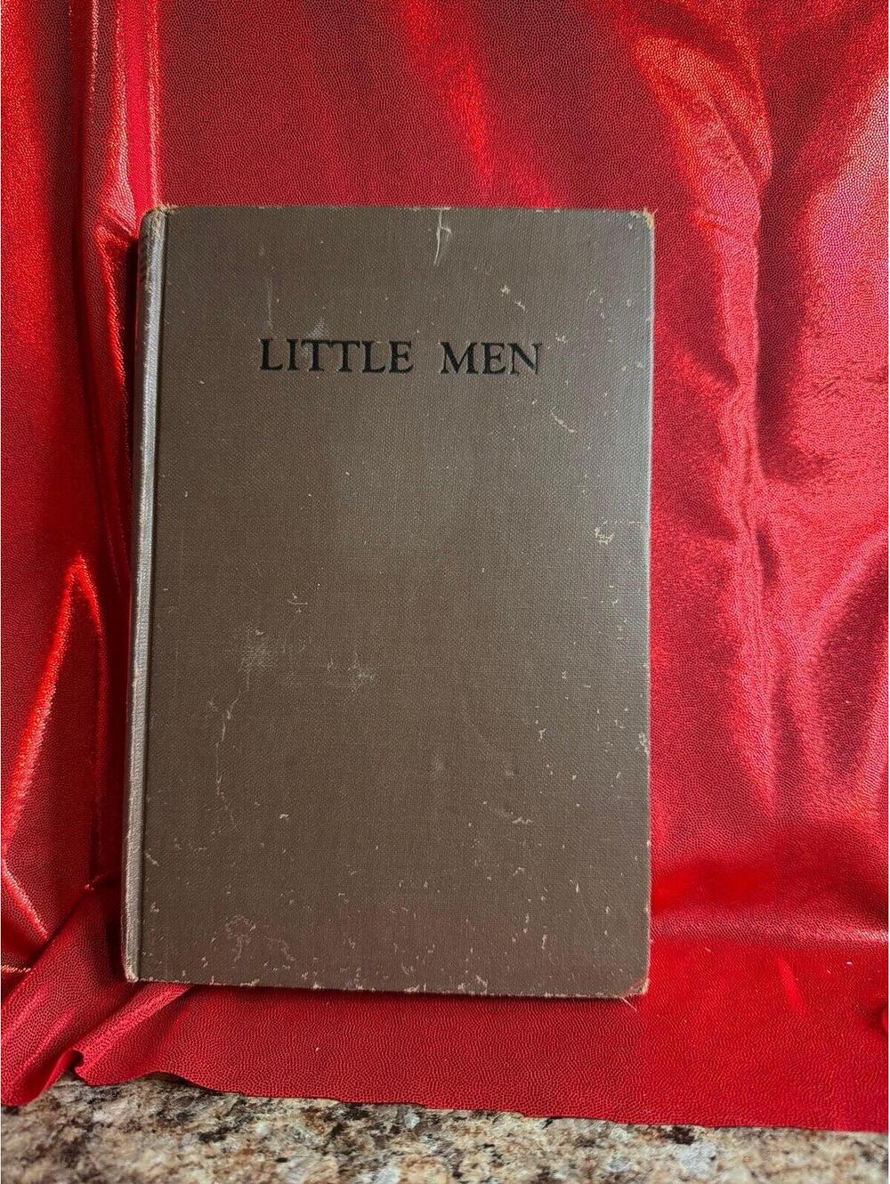 vintage hardcover book is a copy of Little Men by Louisa May Alcott, featuring a